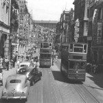 This was one of the principal streets in Victoria. See the bustling throngs, all the flags and streamers on the buildings and across the street. The trams were four wheeled. 1st class passengers traveled on the upper deck, everybody else down below. There seemed no limit to the number carried and three conductors were required to keep order and collect fares.