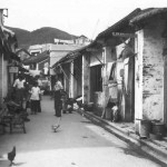 This shows the main street in the Chinese village of Stanley with chickens and ducks running free. Standing in the middle of the street is Tim Tate–Smith.