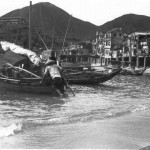 A local fisherman pushing off his boat. A lot of fishing was done from here most of it at night using bright lamps. The boat was the home of the Chinese fisherman and his family who lived on it rather than on land. This was common place for many. Behind it you can see examples of the local architecture.